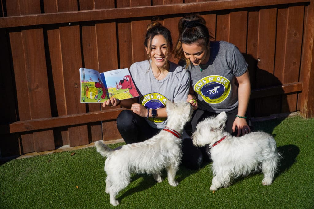 two women with two white haired dogs